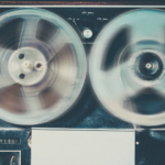 a vintage reel-to-reel tape recorder in action, with both reels spinning.